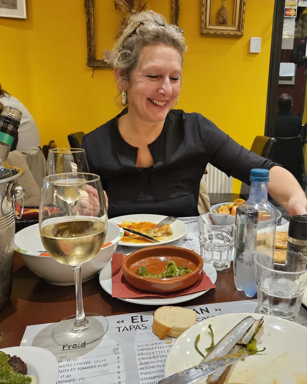 Sabine, lachend aan een tafel vol gerechten