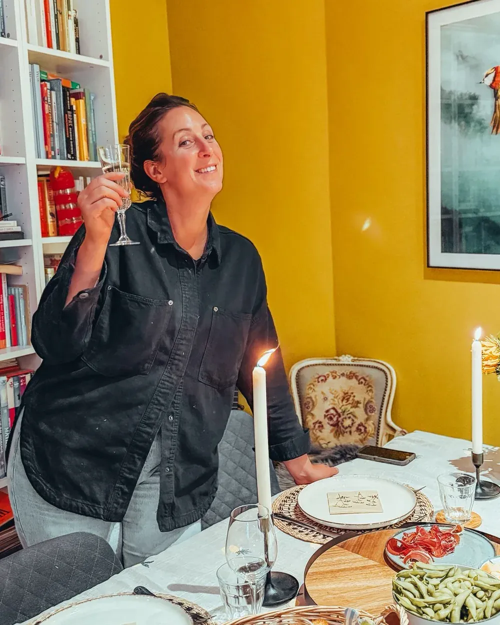 Vicky, lachend met een glas bubbels aan een gedekte tafel